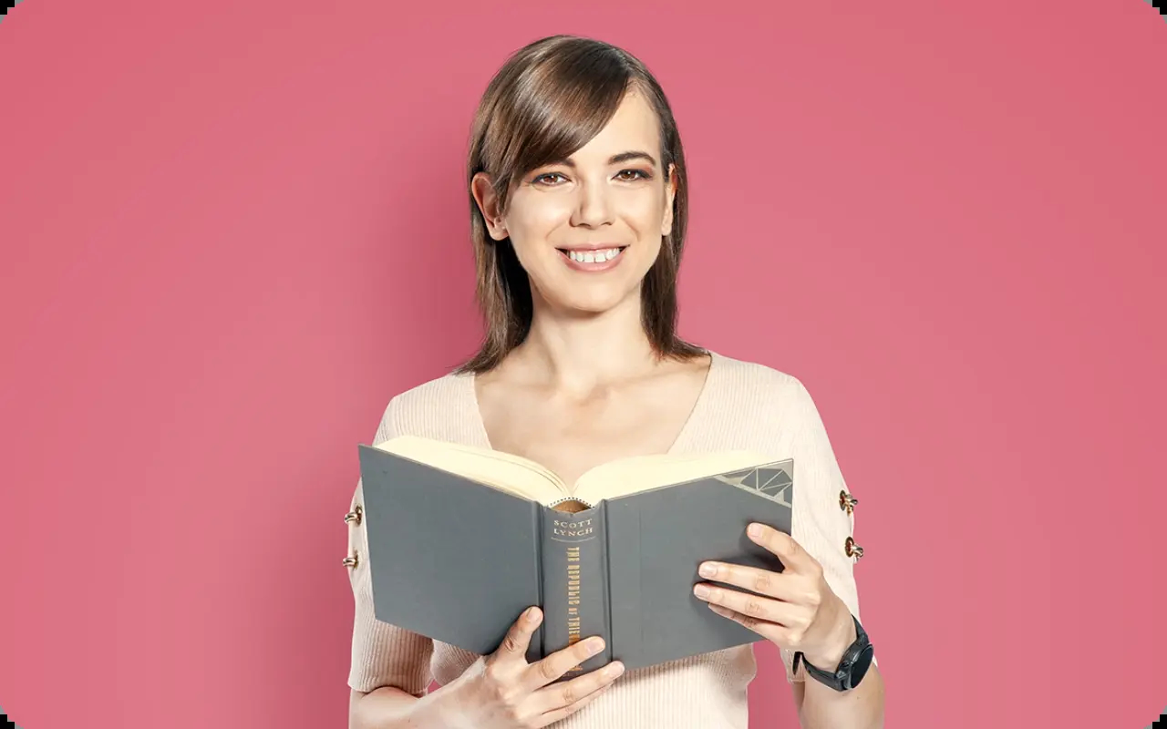 Yoana Viktorova from Amusnet smiling with a book for our hiring and company life website